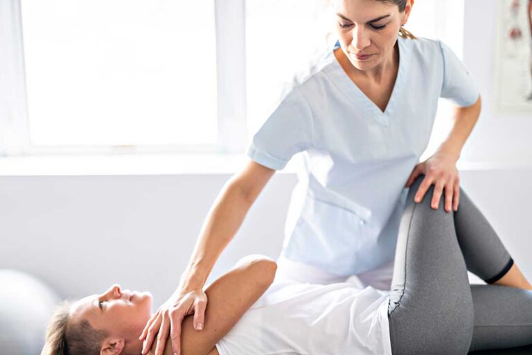 Person gently stretching their lower back beside a chair in a bright home.