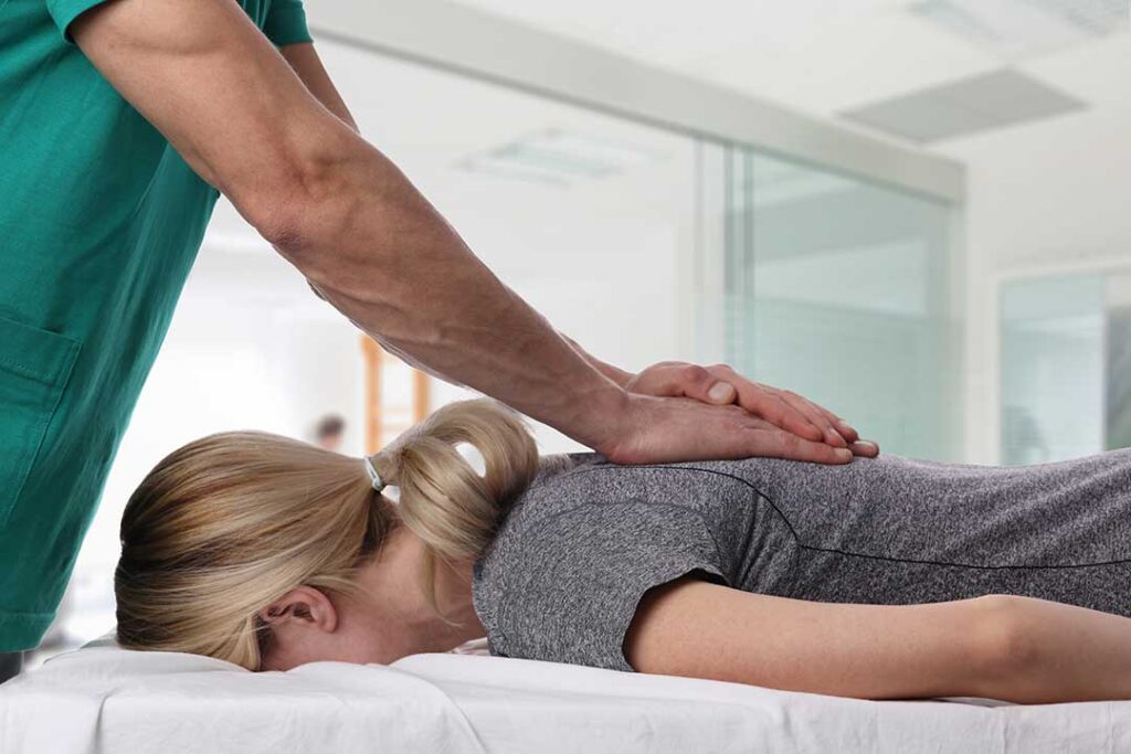 A chiropractor gently adjusting a middle-aged person's back in a calm, home-like clinical setting.